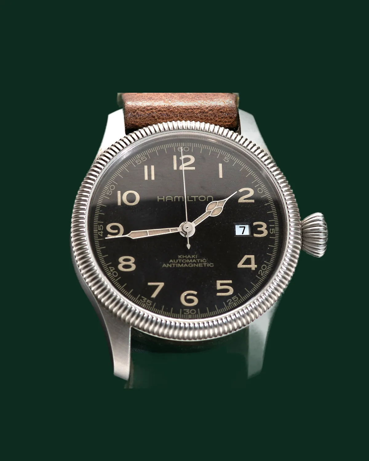 A field watch with a black dial and a leather strap